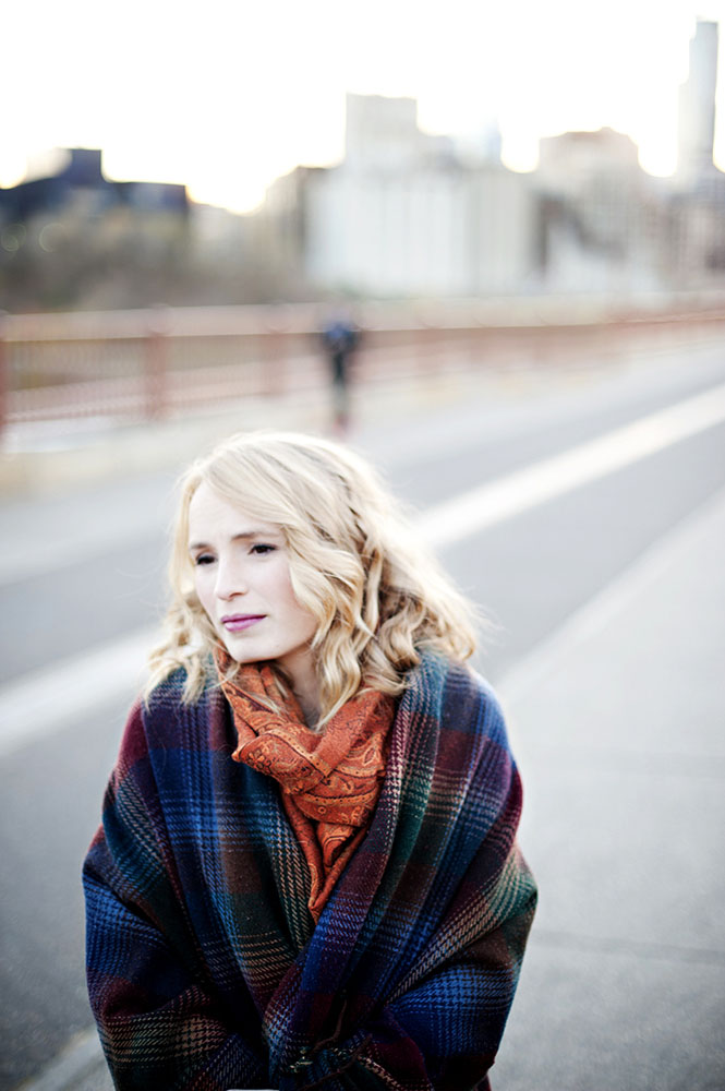 blonde woman with orange scarf and blue and purple blanket