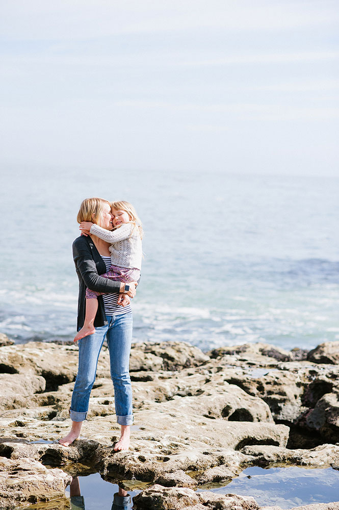Mom and little girl hugging by the ocean