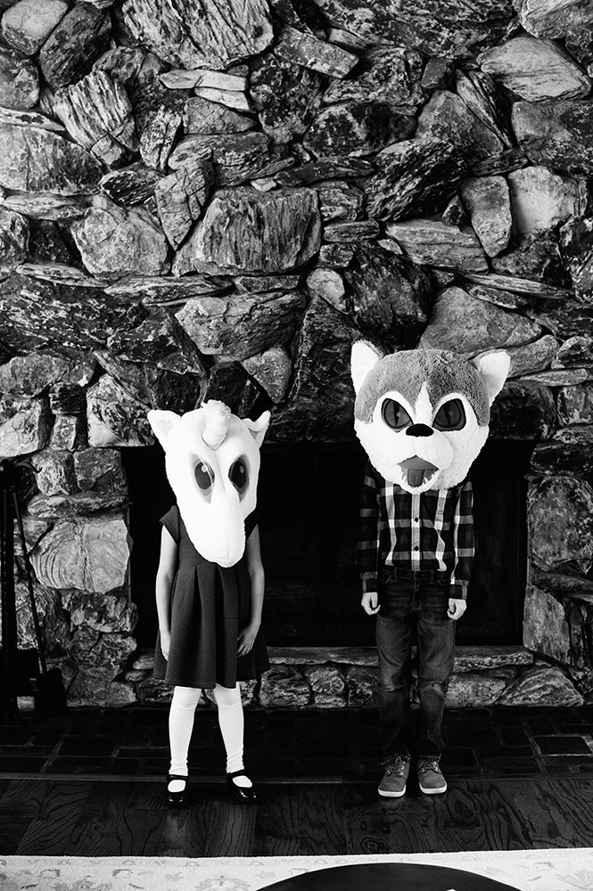 black and white photo of girl and boy with unicorn and wolf heads