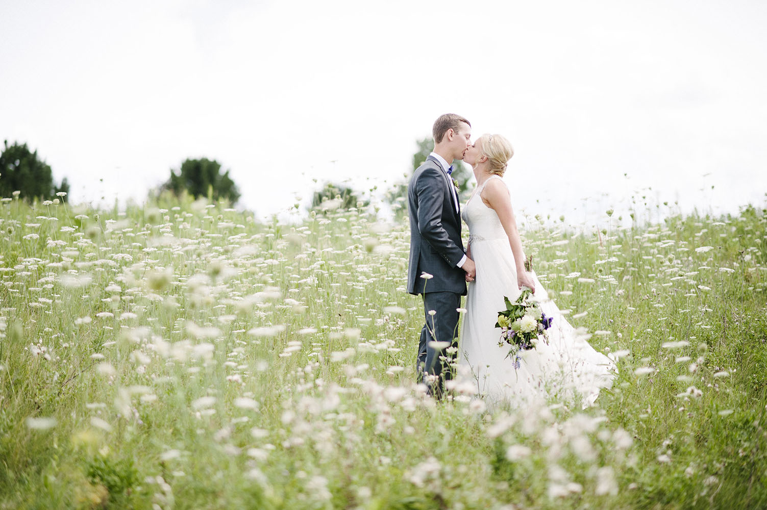 bride and groom kissing in a field of queen anne's lace