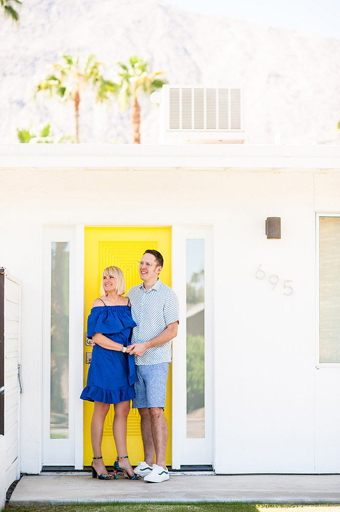 woman in blue dress with guy in blue shorts in front of yellow door of a Palm Springs house