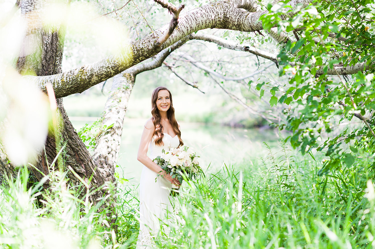 bride with long, dark wavy hair in nature with bouquet