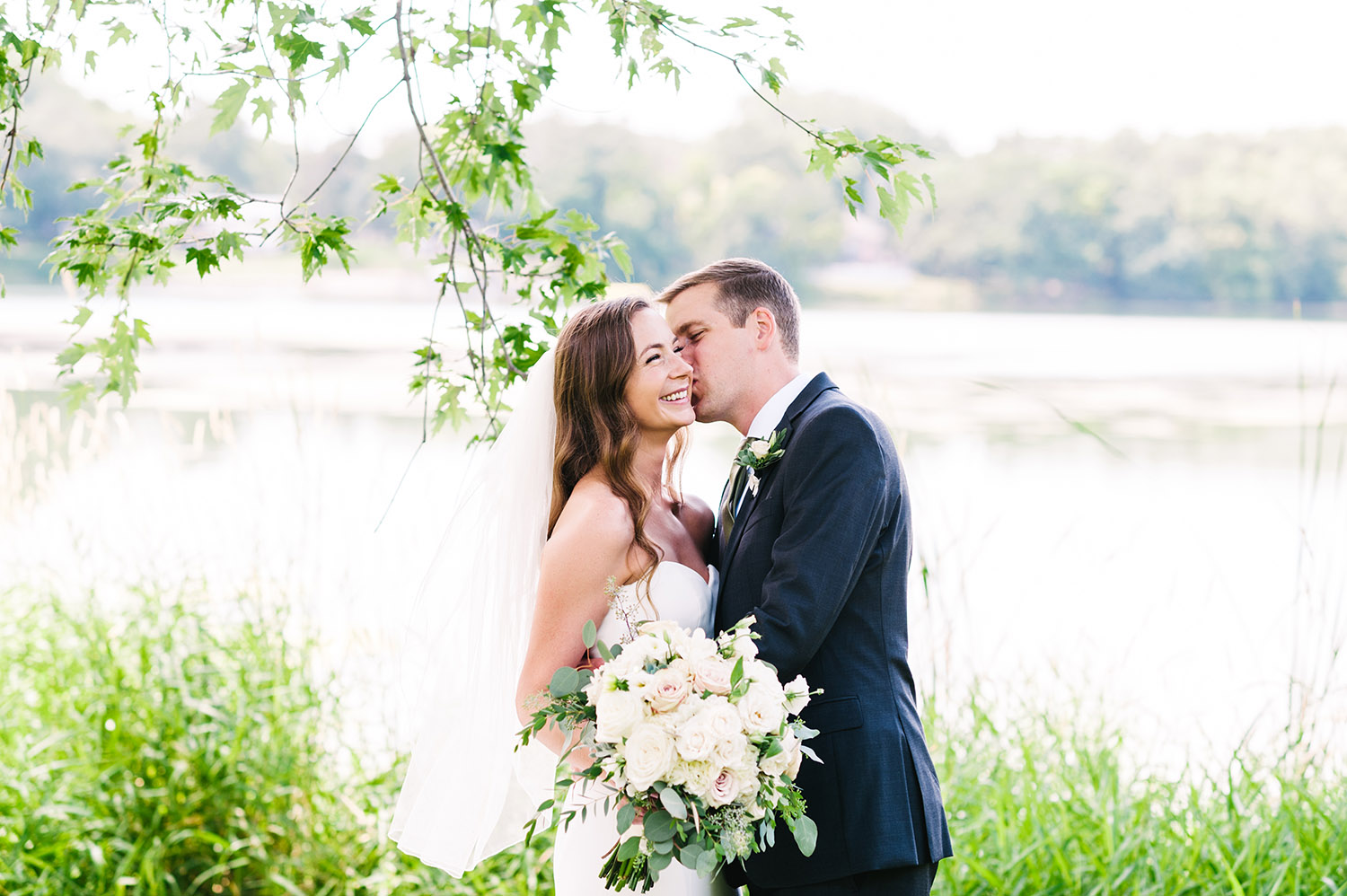 bride and groom in front of a lake