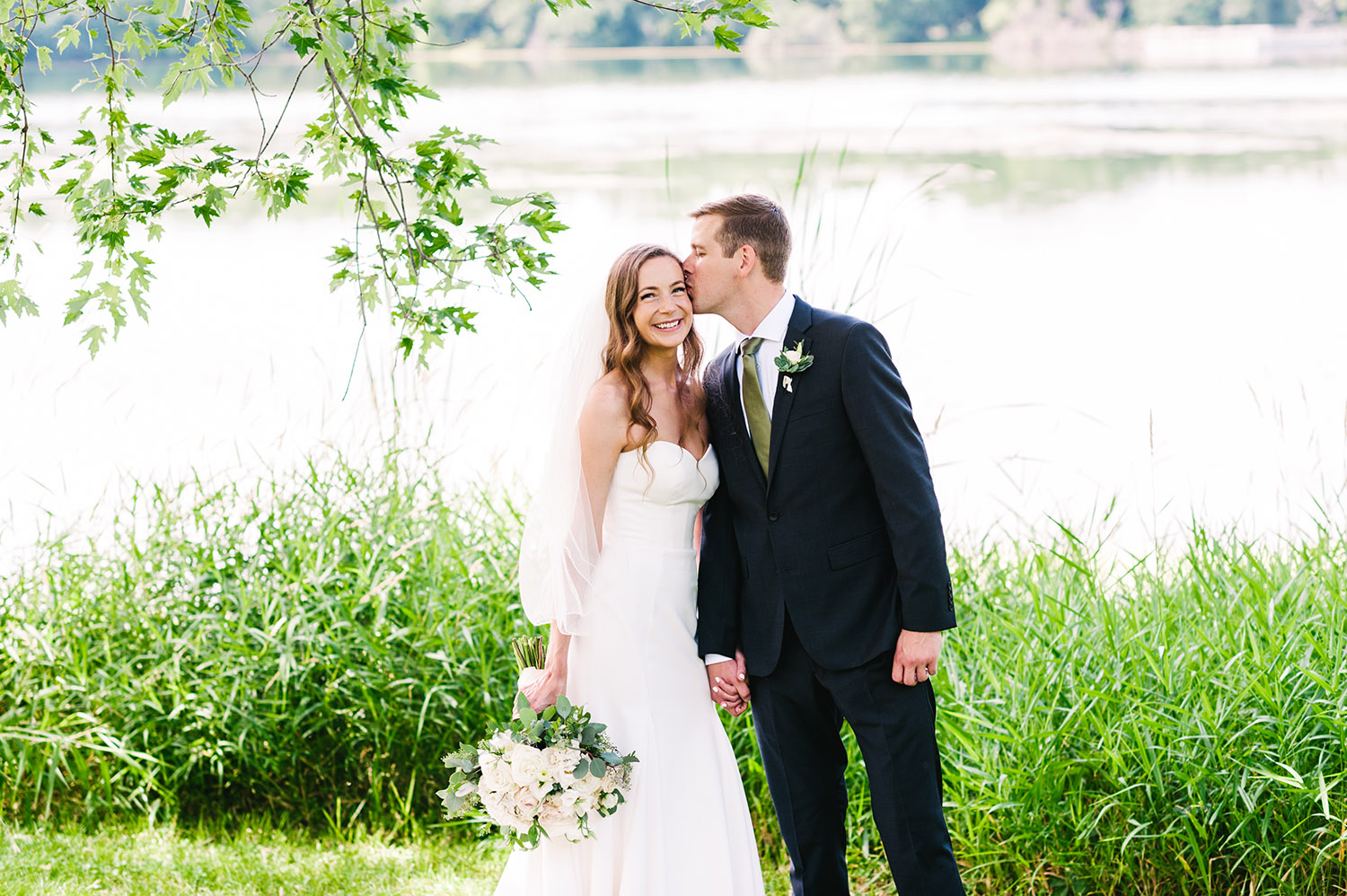 bride and groom in front of a lake