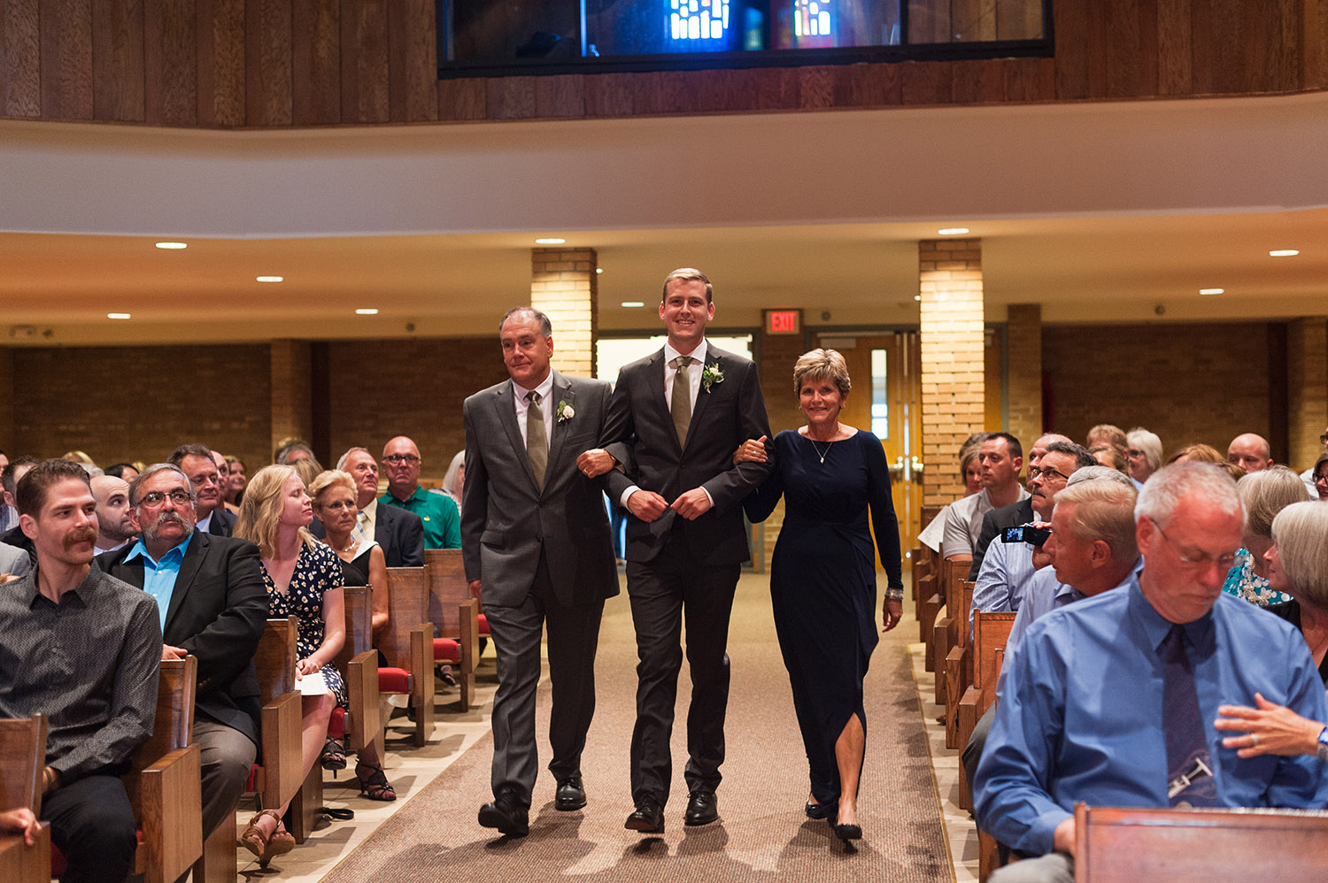 parents walking groom down aisle