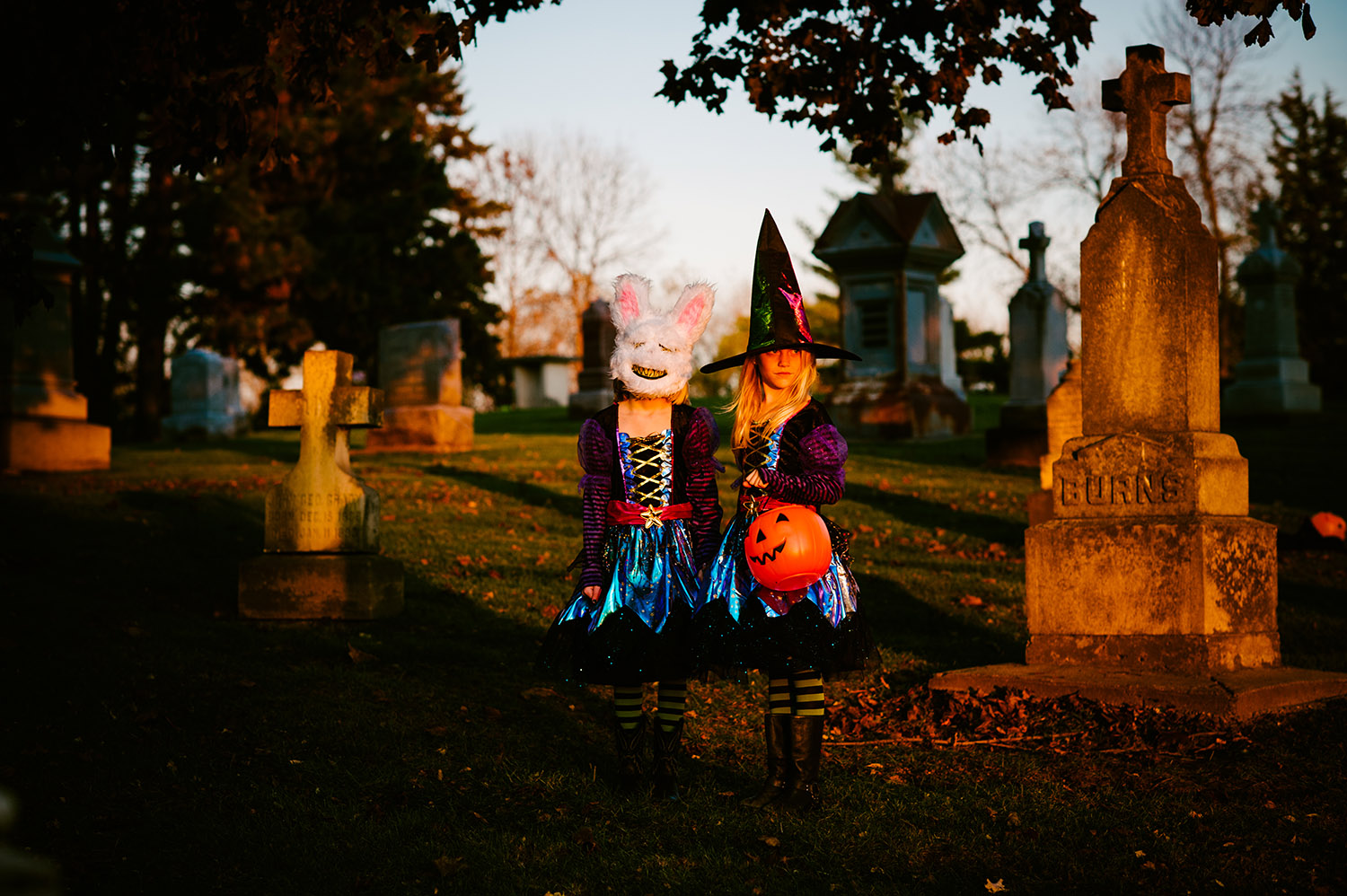 two young girls dressed as witches in a graveyard