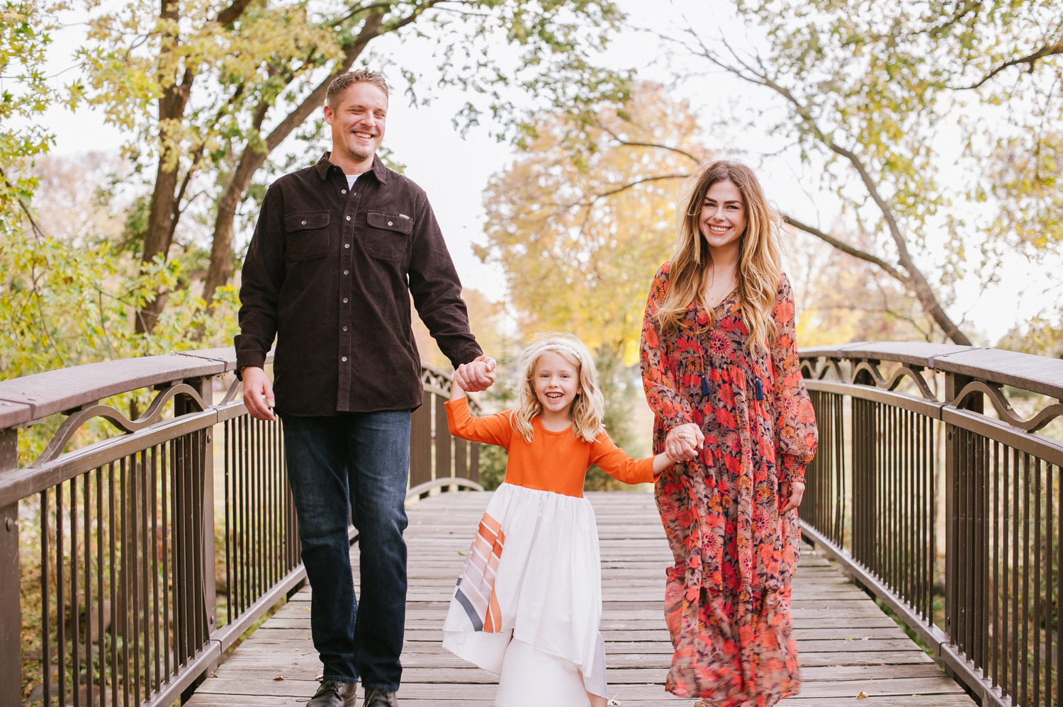 a Fall photo of a family of 3 on a bridge laughing